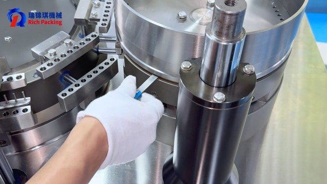 The operator is adjusting the gap between the dosing disc and the copper disc of the capsule filling machine. The operator is adjusting the gap between the dosing disc and the copper disc of the capsule filling machine.